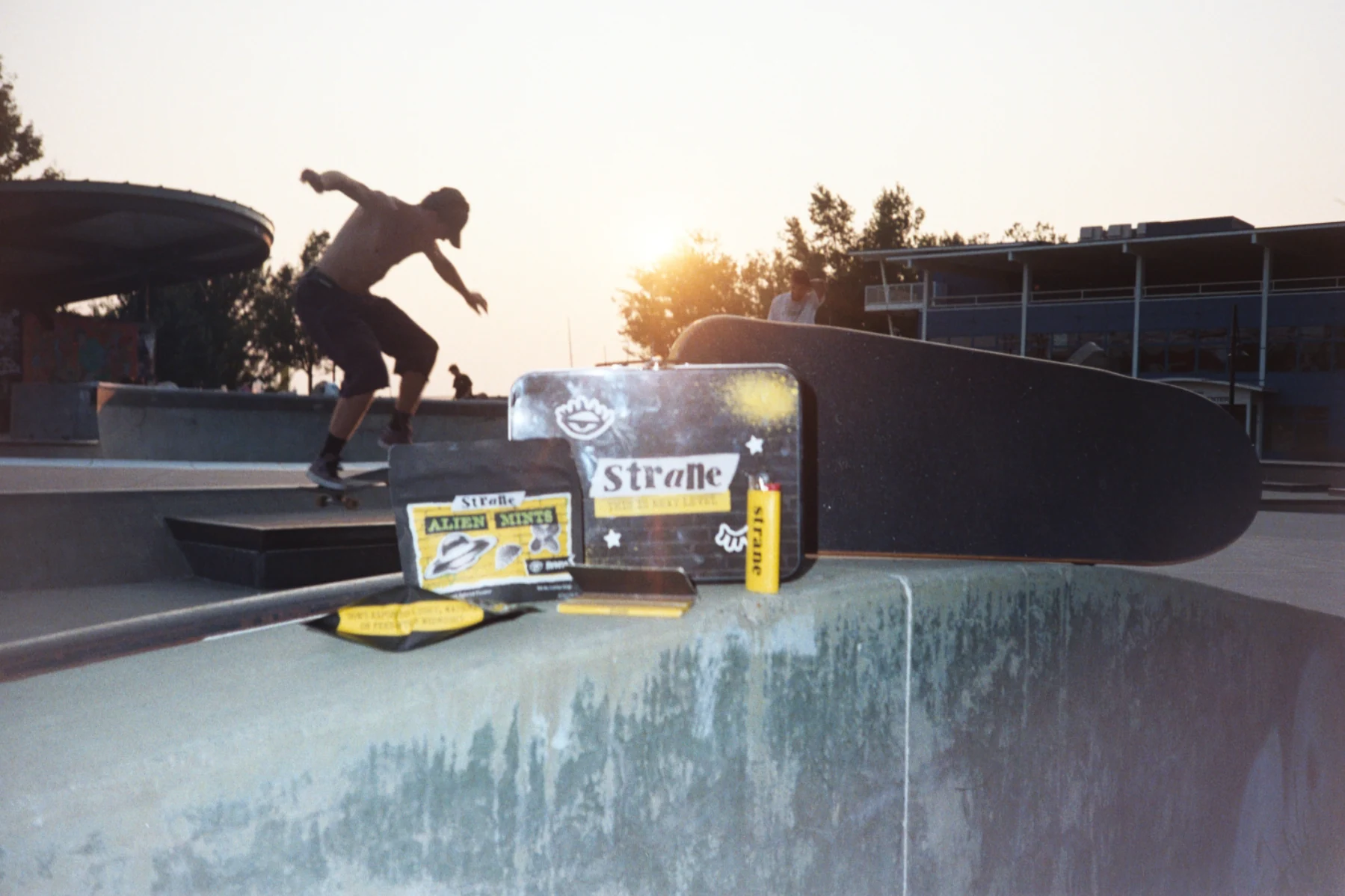 Strane merchandise and products on a skateboard at a sunlit skatepark